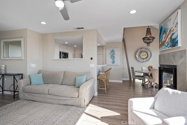 living room featuring hardwood / wood-style floors, ceiling fan, and a premium fireplace