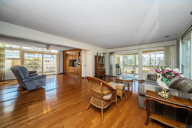 living room featuring a wealth of natural light, ceiling fan, wood-type flooring, and a textured ceiling