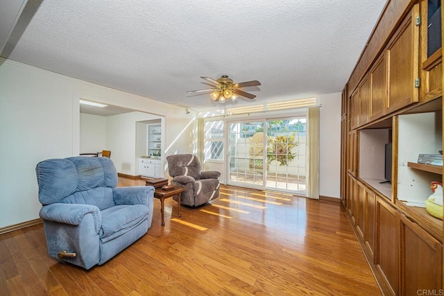 living room with ceiling fan, light hardwood / wood-style floors, and a textured ceiling