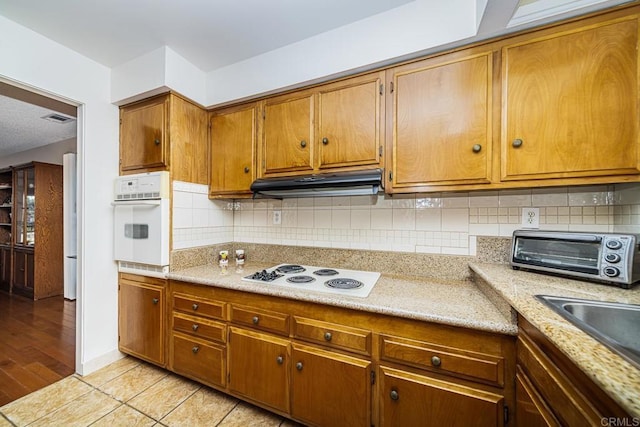 kitchen featuring decorative backsplash, light wood-type flooring, white appliances, and sink