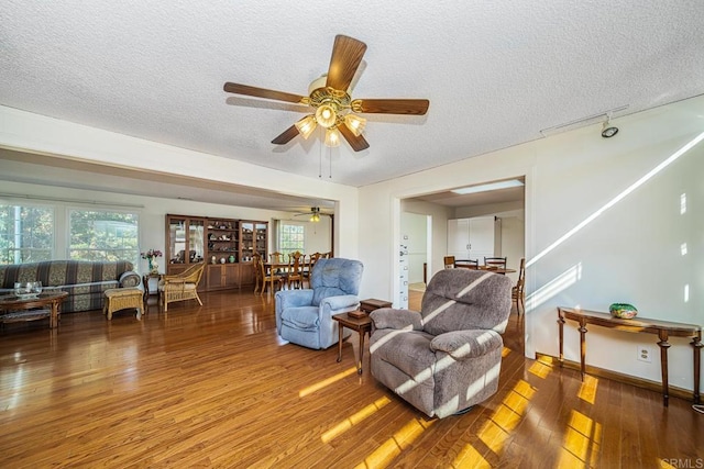 living room featuring ceiling fan, wood-type flooring, and a textured ceiling