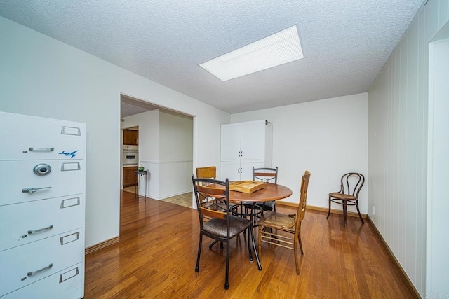 dining area with a textured ceiling, a skylight, and hardwood / wood-style flooring