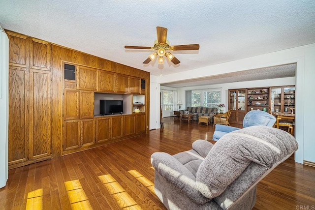 living room with ceiling fan, dark hardwood / wood-style flooring, and a textured ceiling