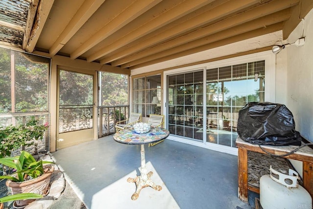 sunroom / solarium featuring beamed ceiling