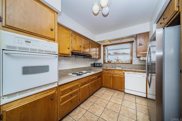 kitchen featuring light tile patterned floors, white appliances, backsplash, and sink