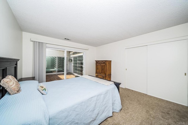 bedroom with access to exterior, a closet, carpet, and a textured ceiling