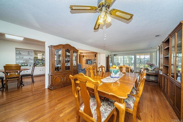 dining space with hardwood / wood-style floors, a textured ceiling, and ceiling fan