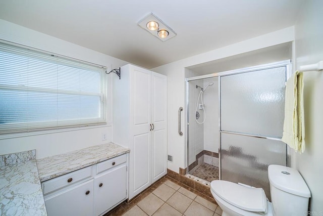 bathroom featuring tile patterned flooring, vanity, toilet, and walk in shower