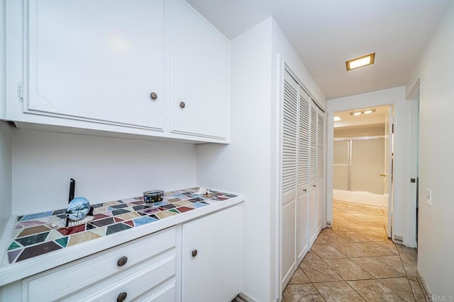 kitchen with white cabinets, light tile patterned floors, and tile countertops