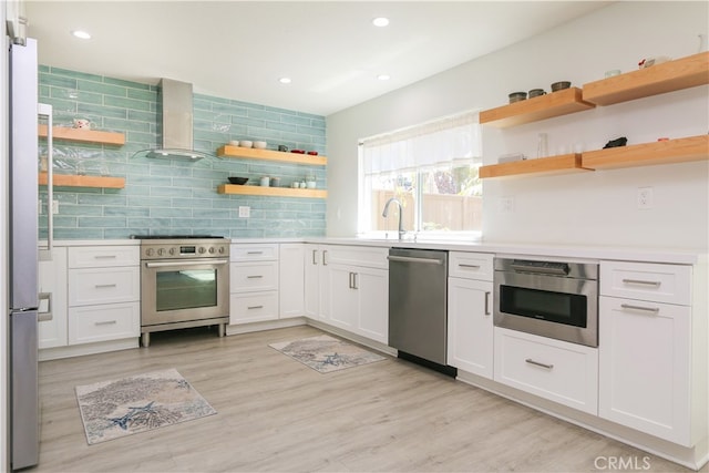 kitchen with appliances with stainless steel finishes, light wood-type flooring, white cabinetry, and sink