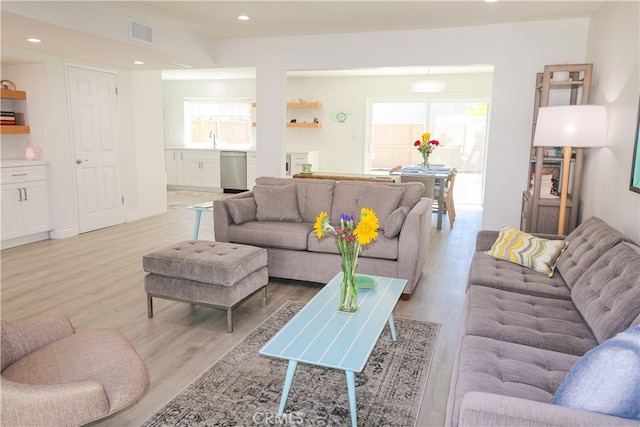 living room featuring sink, light hardwood / wood-style floors, and a healthy amount of sunlight