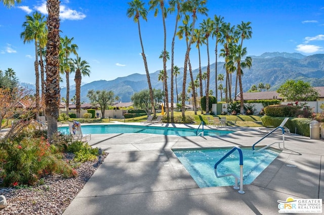 view of pool with a hot tub, a patio area, and a mountain view