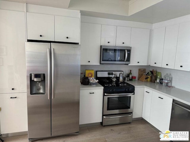 kitchen featuring decorative backsplash, white cabinets, light hardwood / wood-style flooring, and stainless steel appliances