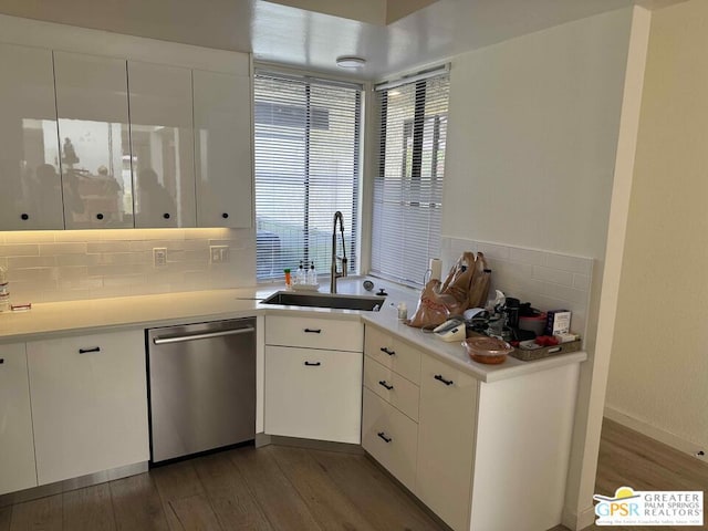 kitchen with tasteful backsplash, sink, dark hardwood / wood-style flooring, white cabinetry, and stainless steel dishwasher