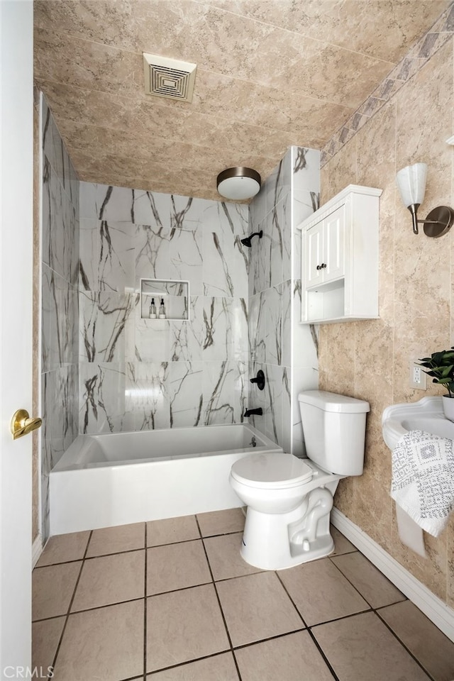 bathroom featuring tile walls, tiled shower / bath combo, toilet, and tile patterned flooring