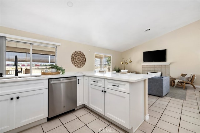 kitchen with lofted ceiling, kitchen peninsula, sink, stainless steel dishwasher, and white cabinets