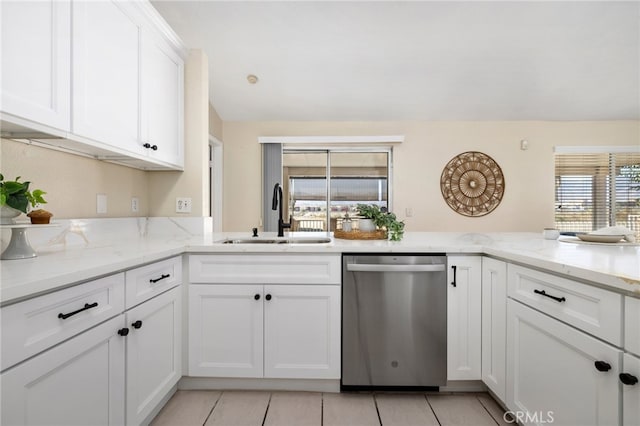 kitchen with stainless steel dishwasher, sink, white cabinets, and light stone countertops