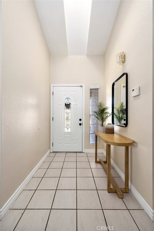 entryway with light tile patterned floors and lofted ceiling