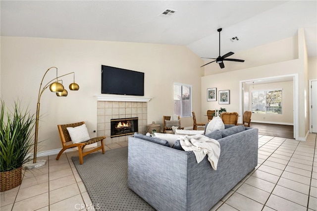 tiled living room with lofted ceiling, a tiled fireplace, and ceiling fan