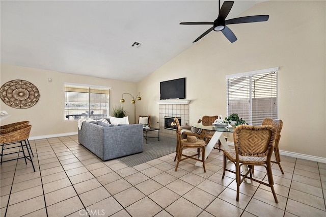 tiled living room with a tiled fireplace, high vaulted ceiling, and ceiling fan