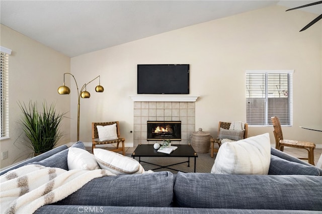 living room with lofted ceiling, hardwood / wood-style floors, a tiled fireplace, and ceiling fan