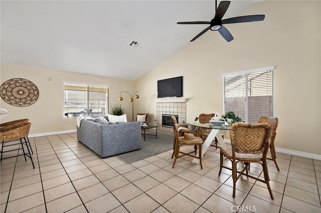 tiled living room with high vaulted ceiling, a tile fireplace, and ceiling fan