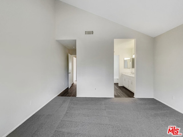 unfurnished bedroom featuring lofted ceiling, dark hardwood / wood-style floors, and ensuite bathroom