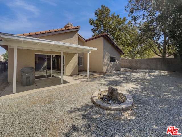 back of property featuring a fire pit and a patio area