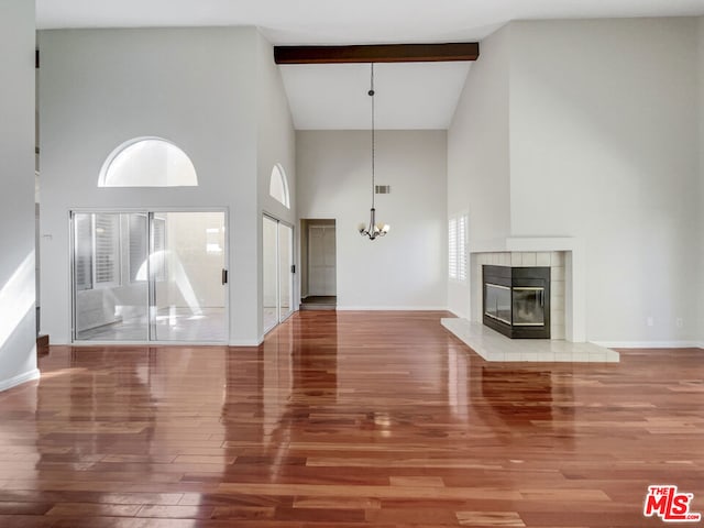 unfurnished living room with wood-type flooring, beamed ceiling, high vaulted ceiling, and a wealth of natural light