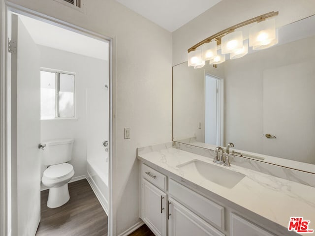 full bathroom featuring wood-type flooring, separate shower and tub, vanity, and toilet