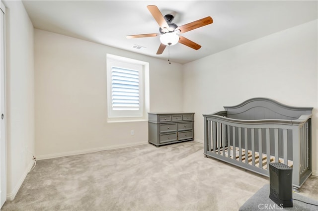 carpeted bedroom with a nursery area and ceiling fan