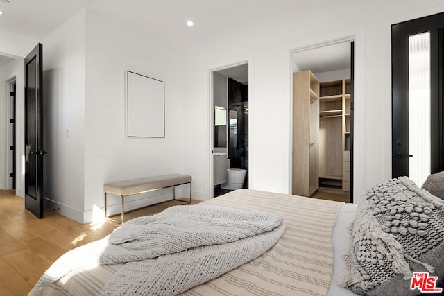 bedroom featuring connected bathroom, light hardwood / wood-style flooring, a spacious closet, and a closet