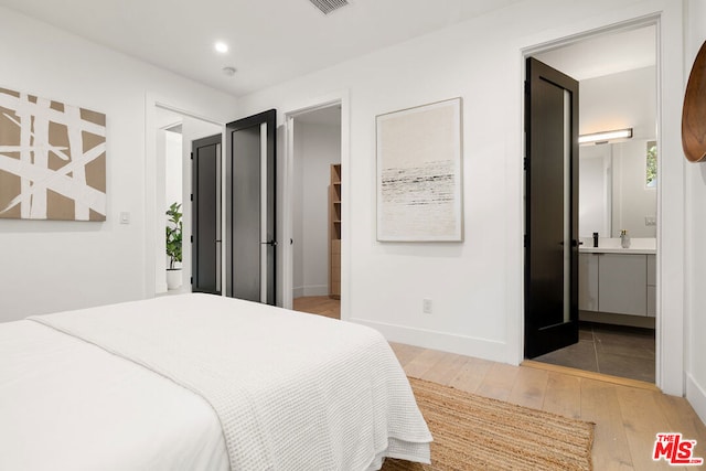 bedroom with wood-type flooring and ensuite bath