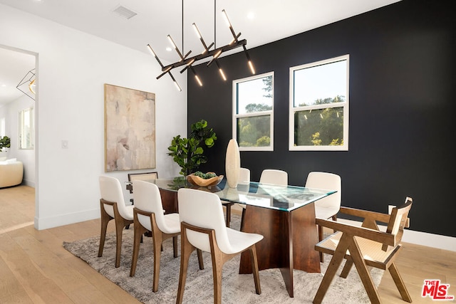 dining room with light wood-type flooring and an inviting chandelier