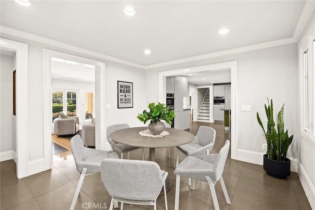 dining space featuring dark tile patterned flooring and ornamental molding