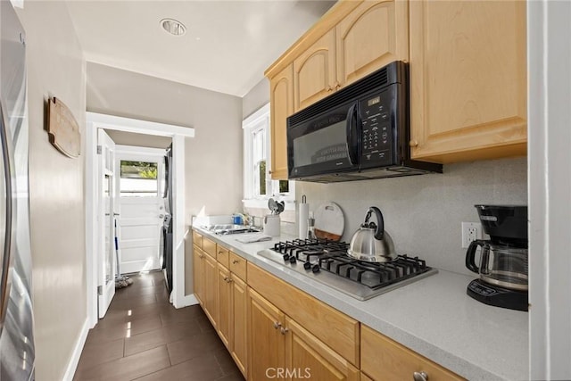 kitchen featuring sink, light brown cabinets, dark tile patterned floors, and stainless steel gas stovetop