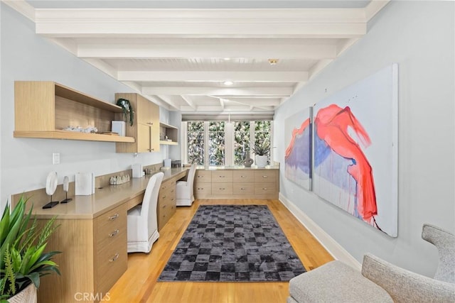 kitchen featuring beamed ceiling, light brown cabinets, built in desk, and light hardwood / wood-style flooring