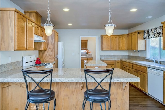 kitchen with a center island, dark wood-type flooring, sink, a kitchen bar, and white appliances