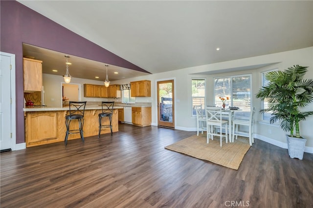 interior space featuring white dishwasher, kitchen peninsula, decorative light fixtures, dark wood-type flooring, and a breakfast bar