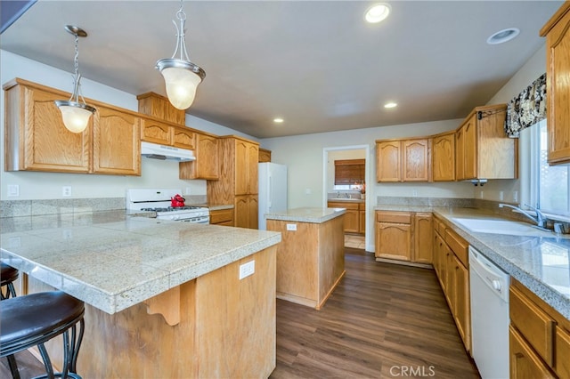 kitchen featuring pendant lighting, a kitchen island, a kitchen breakfast bar, white appliances, and dark hardwood / wood-style flooring