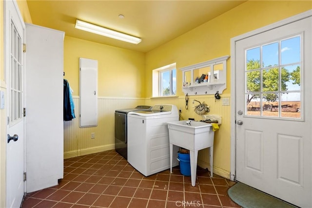 washroom with a healthy amount of sunlight, wooden walls, washing machine and dryer, and dark tile patterned floors