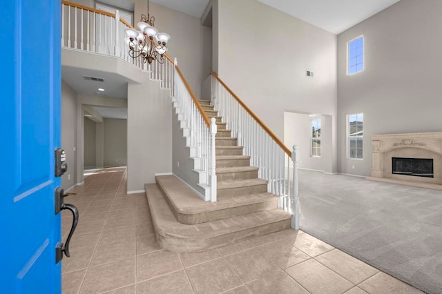 entryway featuring a high end fireplace, a high ceiling, light carpet, and plenty of natural light