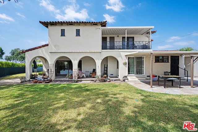 back of property with a yard, a balcony, and a patio area