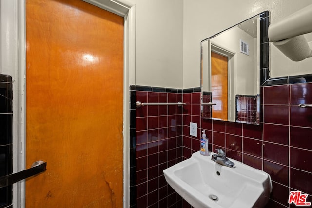 bathroom with sink and tile walls