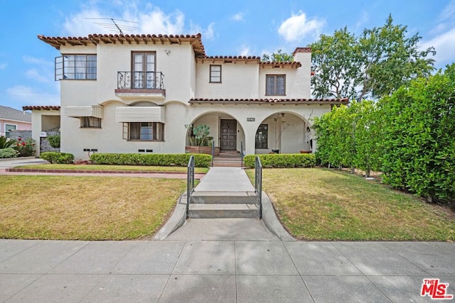 mediterranean / spanish-style home featuring a balcony and a front yard