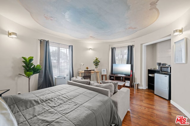 bedroom featuring stainless steel fridge and hardwood / wood-style flooring