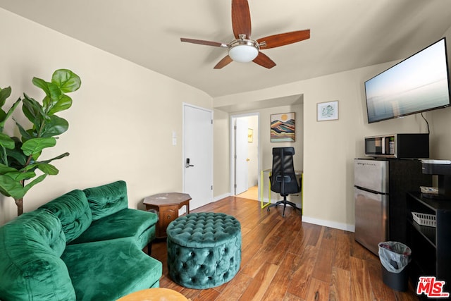 living room featuring ceiling fan and dark hardwood / wood-style flooring