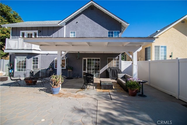 rear view of property with a balcony, a patio area, and a fire pit