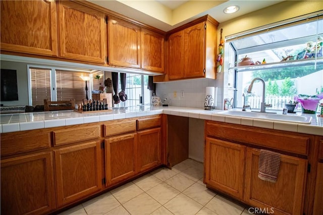 kitchen featuring light tile patterned flooring, tile countertops, sink, and decorative backsplash