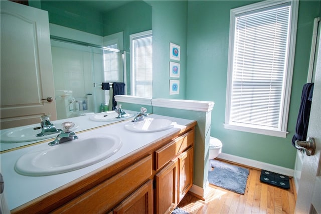 bathroom with a wealth of natural light, hardwood / wood-style flooring, vanity, and toilet